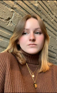 a woman wearing a brown turtleneck sweater and gold necklace