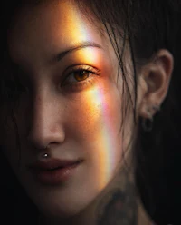 a woman with tattoos and piercings with a rainbow light shining on her face