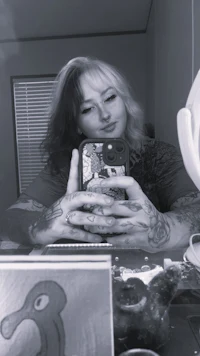 a woman with tattoos taking a selfie in a mirror